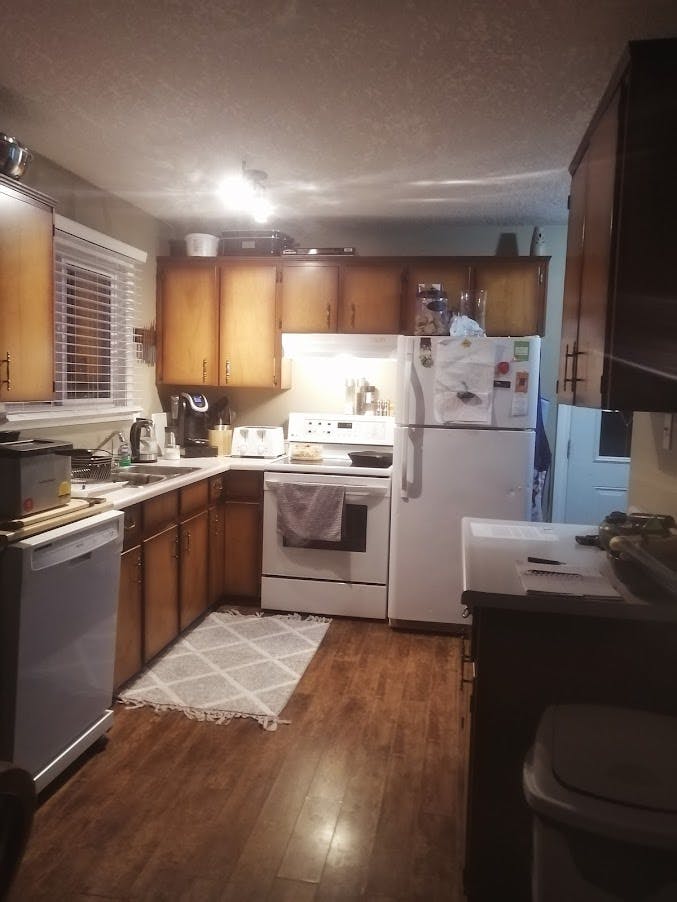 Dated looking kitchen with sunburst cupboards and white appliances
