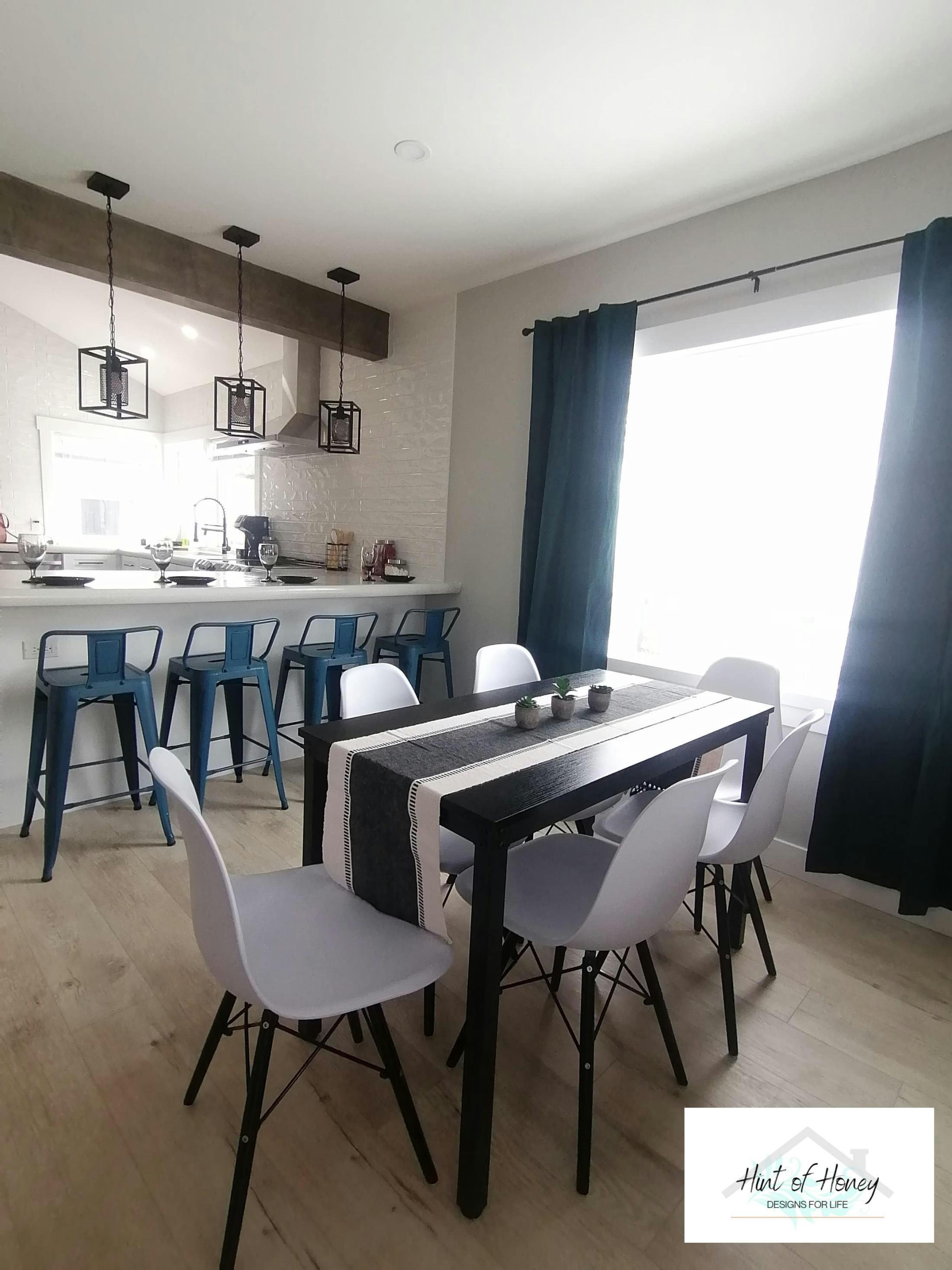Staged dining room table with table runner and small green plants as centerpiece