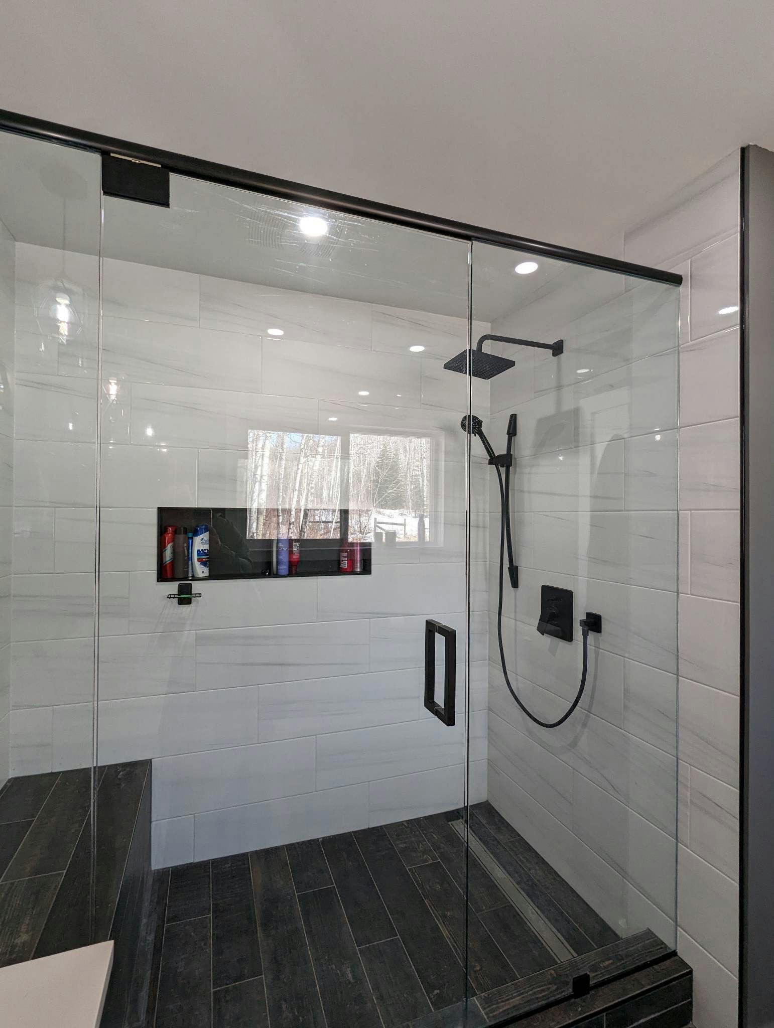Custom glass shower with solid glass walls and black accents