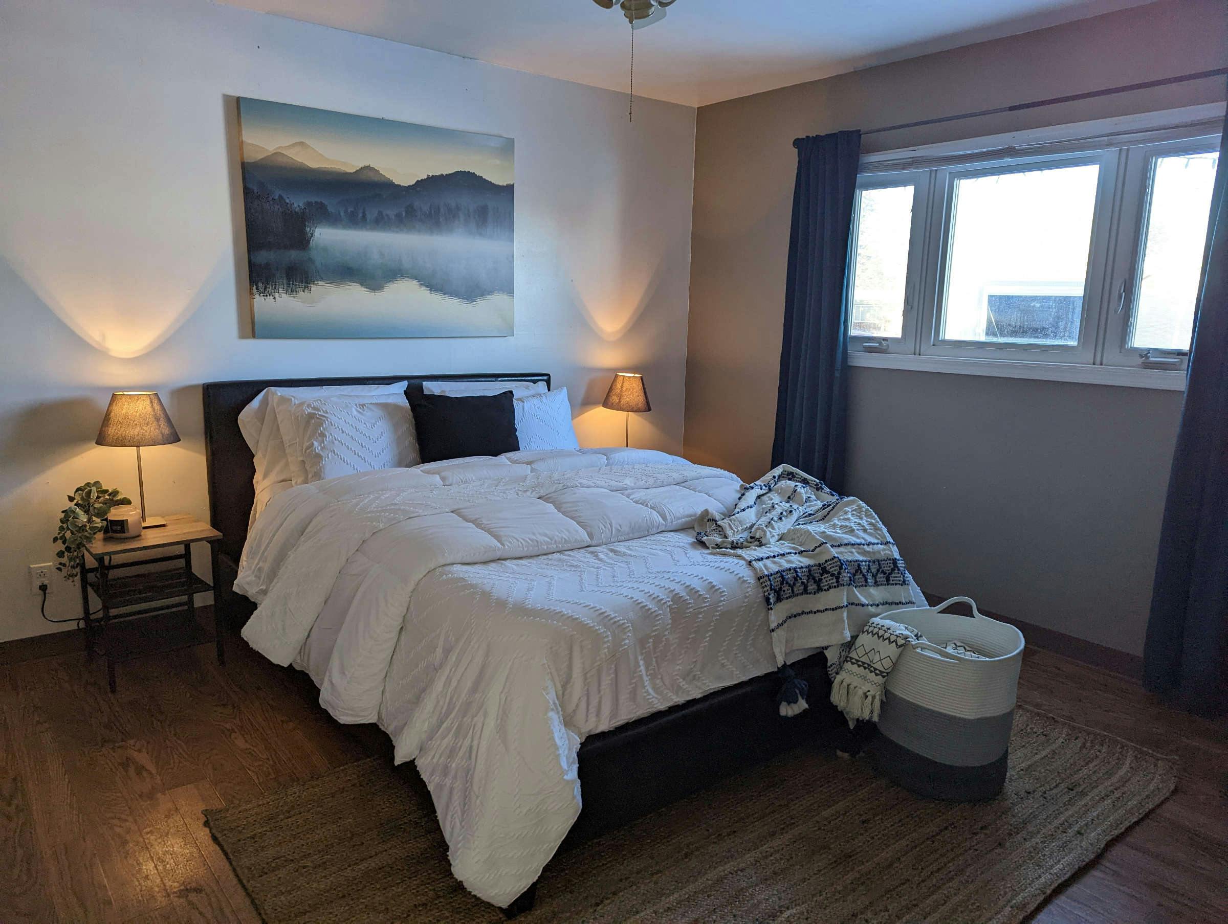 Bedroom staged with soft warm lamps and bed with plush white bedding