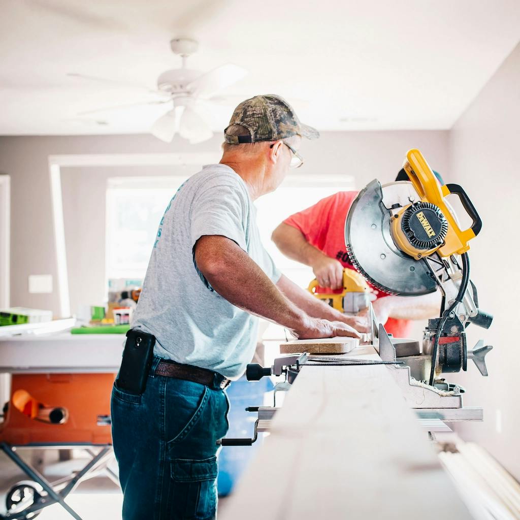 A man cutting a piece of wood down to size with a miter saw