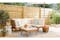 Gartenmöbel aus Holz mit hellen Bezügen und Sonnenschirm