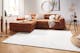 Heller Teppich vor Couch in Naturfarben mit goldenen Dekoelementen im Wohnzimmer