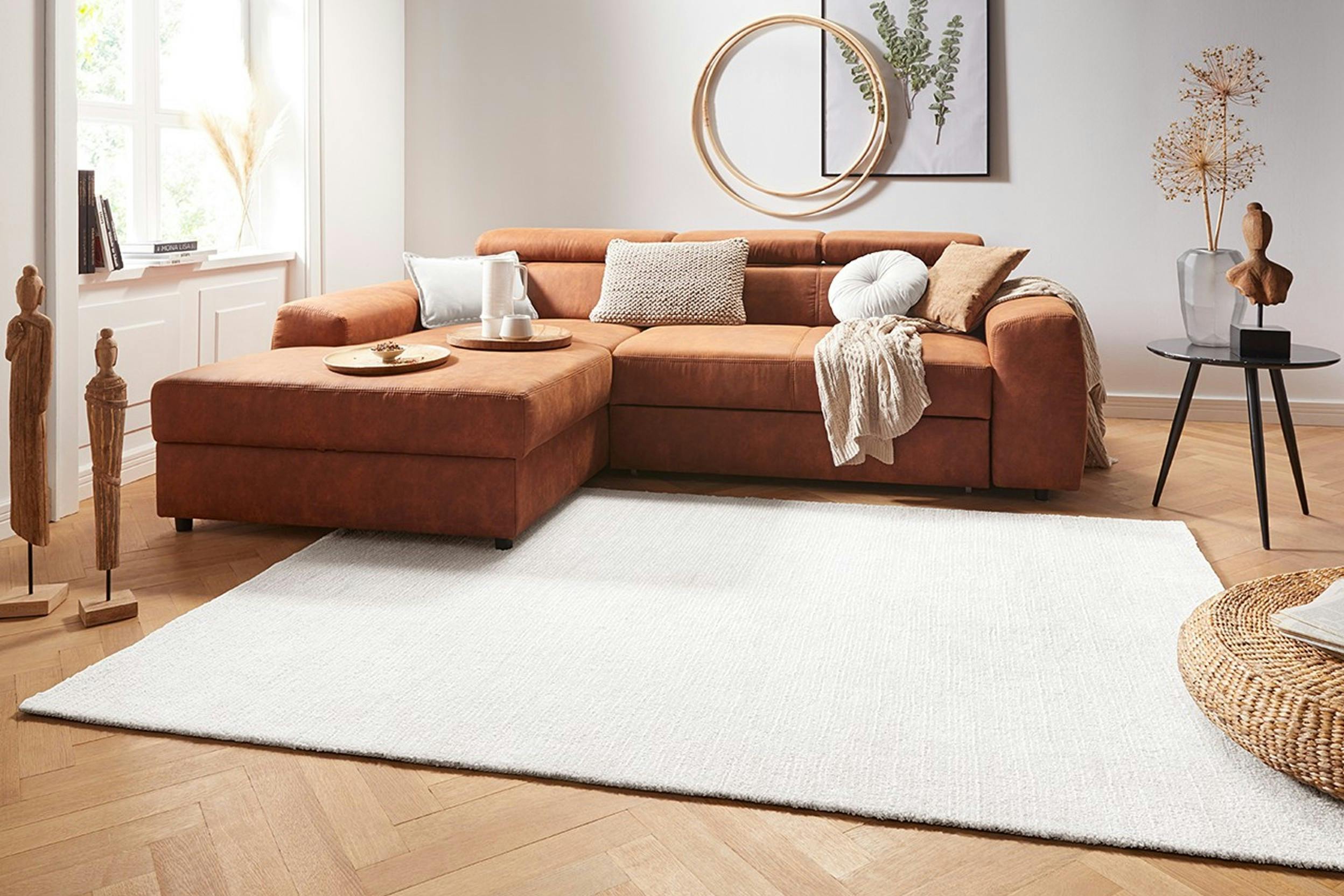 Heller Teppich vor Couch in Naturfarben mit goldenen Dekoelementen im Wohnzimmer