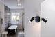 Schwarze, bewegliche Badezimmer-Wandleuchte neben einem Spiegel, dahinter eine Badewanne