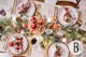 Table de fête avec décoration traditionnelle en rouge, vert sapin, et blanc, vaisselle dorée et scintillement des bougies