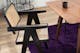 Chaise cannée devant une table de salle à manger en bois massif foncé, tapis violet et desserte noire. 
