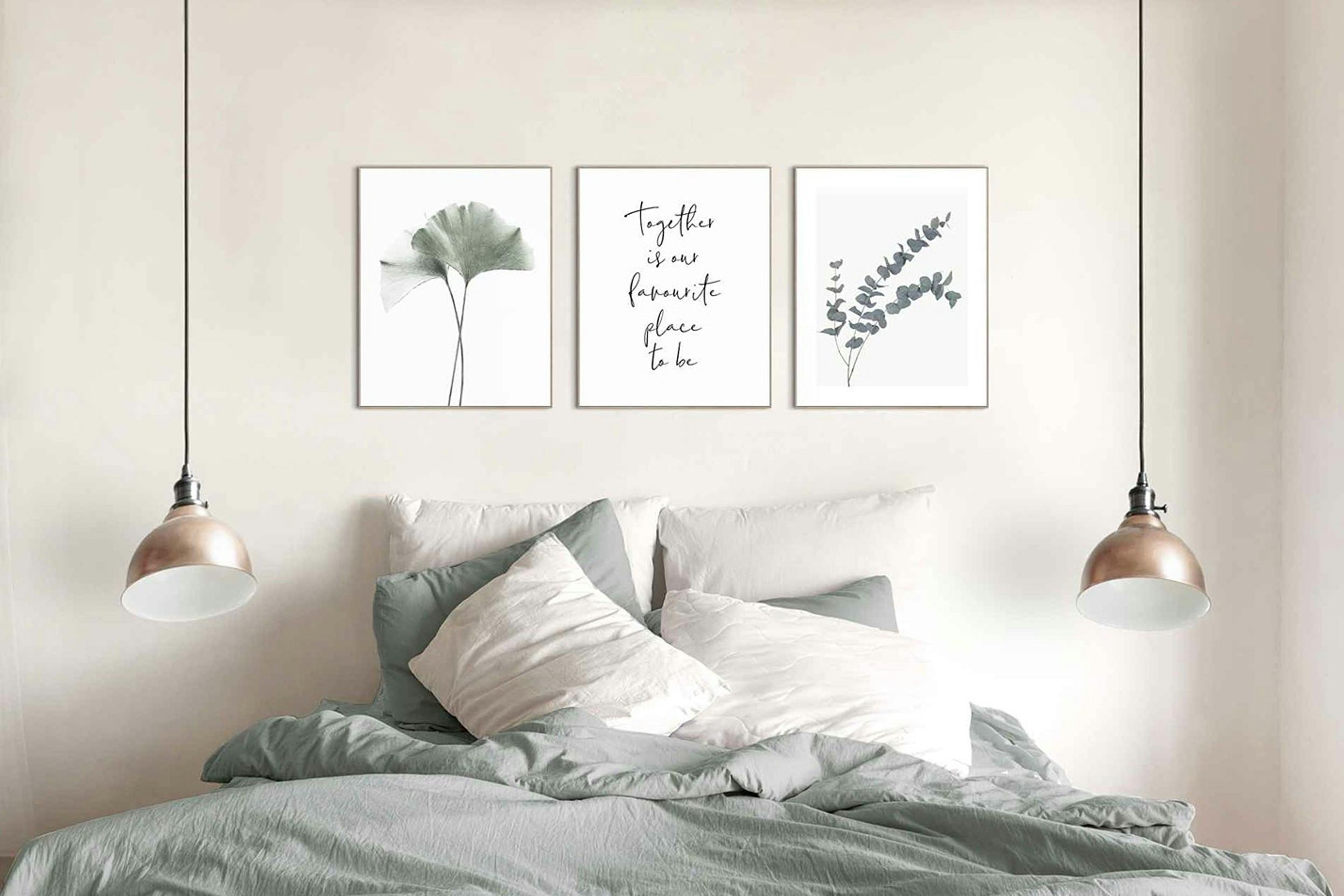 Set van drie afbeeldingen boven het bed aan een crèmekleurige wand.