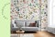 Canapé gris devant un mur avec papier peint à imprimé floral, une table basse ronde en bois, des décorations de table ainsi qu'un tapis gris ; à côté, de beaux vases dans les tons verts.