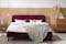 Doppelbett in Bordeauxrot mit Bettdecken und auf Teppich