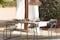 Terrasse in mediterranem Finca-Style mit Gartemöbeln aus Akazienholz und Stahlgestell, die kombiniert sind mit cremefarbenen Outdoor-Textilien, einer Pendellampe in Stroh-Optik und weißen Vorhängen