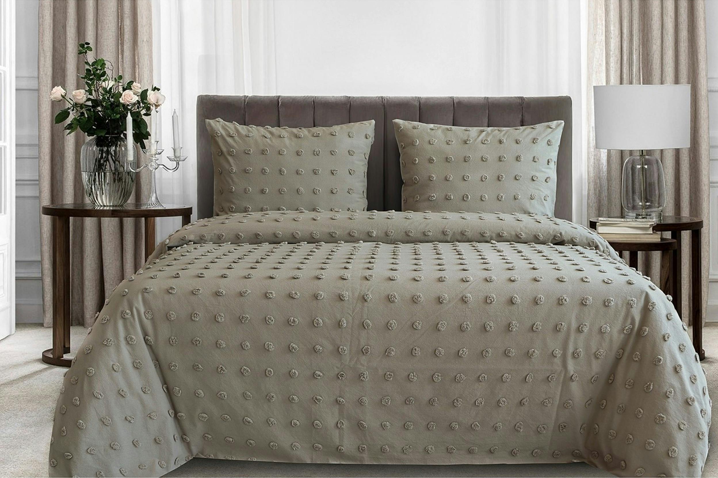 Salbeigrüne Perkalbettwäsche auf grauem Polsterbett mit eleganten Nachttischen