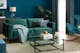 Salon dans les tons verts et bleus avec canapé et rocking chair en velours et table basse en verre