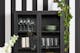 Zwart vitrinekast van metaal met glazen deuren en een opbergplank, voor een zwart-wit gestreept behang.