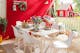 Weiße Gartenmöbel im Skandi-Stil vor typisch skandinavisch roter Hauswand und dekoriert mit urigen Accessoires wie einer Blechgießkanne und Blumenkränzen im Midsommar-Look.