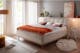Photo d'un lit avec un cadre de lit capitonné, en tissu beige, dans une chambre cosy