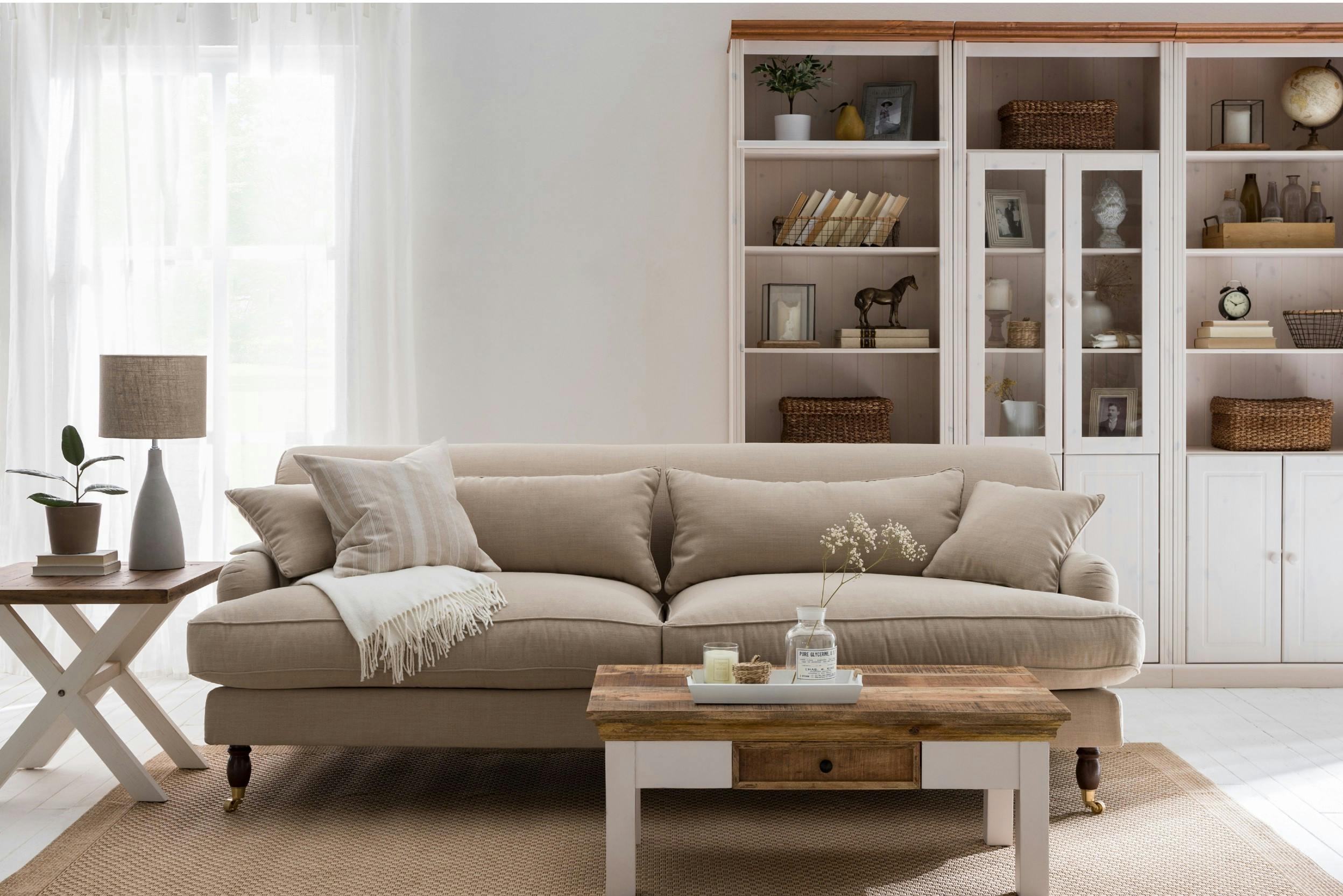 Cremefarbenes Sofa mit weißen Möbeln im Landhausstil