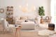 Canapé beige en tissu dans un salon avec tapis, plante et lampes, le tout de couleur claire