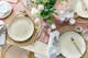 Kleurrijk gedekte paastafel met servies, kandelaars, bloemen en paasdecoratie.
