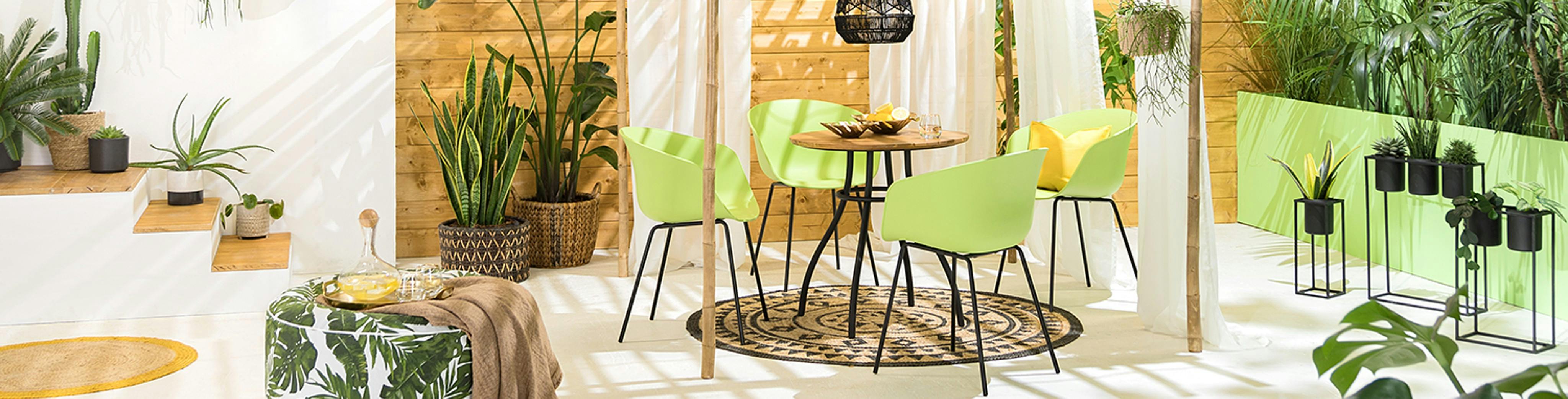 Grüne Gartenstühle aus Kunststoff auf einer geräumigen Terrasse mit vielen Pflanzen
