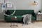 Samtsofa in der Trendfarbe Smaragdgrün in einem natürlich und wohnlich eingerichteten Wohnzimmer mit Couchtischen aus Holz, einer Glasleuchte, einer gemütlichen Kuscheldecke, dazu ein hellbeiger Teppich.