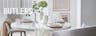 Table ronde blanche avec vaisselle en porcelaine, vase en céramique, bougeoir en marbre et nappe en lin blanc ; les planches en bois apportent une touche scandinave.