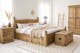 Chambre avec meubles en bois clair de style maison de campagne, tapis beige, linge de lit blanc, décoration murale en osier, vase avec herbes de la pampa.