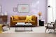 Wohnzimmer mit fliederfarbener Wand und Bildern, dazu ein senfgelbes Sofa mit gelbem Kissen, ein Couchtisch aus schwarzem Metall, ein brauner Ledersessel in Flechtoptik sowie ein Retro-Sessel mit grauem Polster und Holzbeinen.
