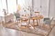 Table de salle à manger Voksa par Ars Natura, une marque exclusive home24, avec de la vaisselle BUTLERS bleu clair et blanche et des décorations de Pâques colorées, ainsi que des chaises grises de style scandinave, une enfilade blanche et un tapis beige.