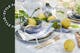 Gedeckter Tisch mit Limoncello Spritz in geriffelten Gläsern von BUTLERS, dazu goldenes Besteck, blaugraues Geschirr und saftige Zitronen zur Deko.