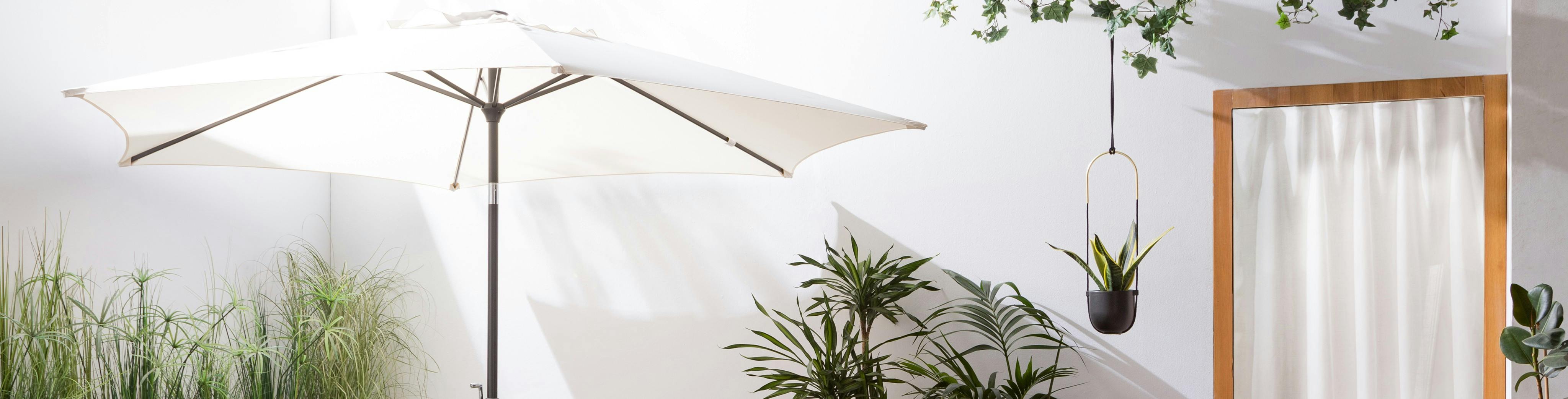 Weißer Sonnenschirm im Detail auf einer Terrasse mit Pflanzen