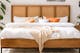 Schlafzimmer mit Bett und Nachttisch mit Wiener Geflecht, davor links ein Kaktus im Flechtkorb und rechts ein Sideboard mit Türen in Wiener Geflecht