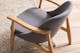Gros plan sur un fauteuil gris aux accoudoirs en bois