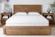 Grosse Matratze für Doppelbett mit zwei Kissen und Bettmöbeln aus Massivholz.