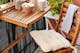 Petit balcon verdoyant à l'aspect chaleureux grâce à des meubles pliants en bois et un tapis extérieur BUTLERS dans les tons beiges.