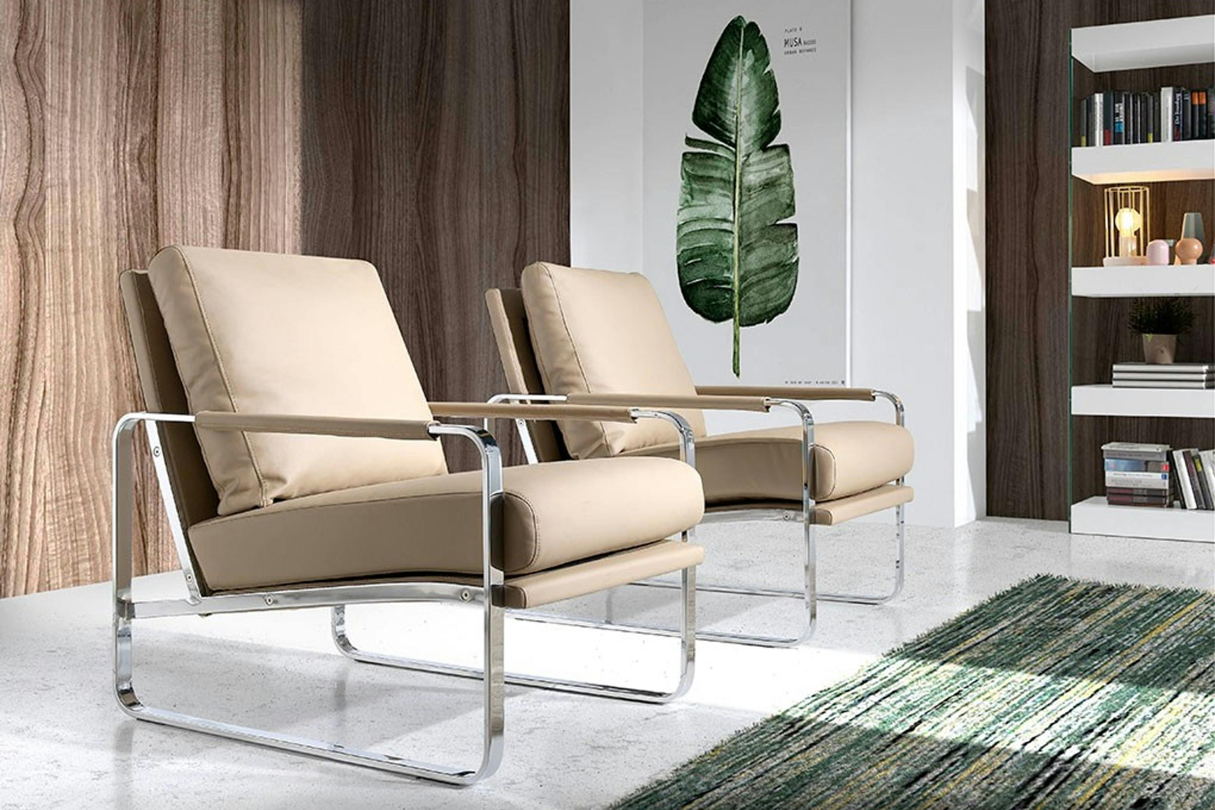 Zwei moderne Sessel mit Chromgestell in einem Raum mit grünem Teppich und Wandbild