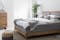 Schlafzimmer mit Massivholzmöbeln, Pouf und Plaid in Grau- und Braunnuancen