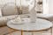 Salon dans des nuances de beige avec table basse en marbre blanc avec une structure en métal doré