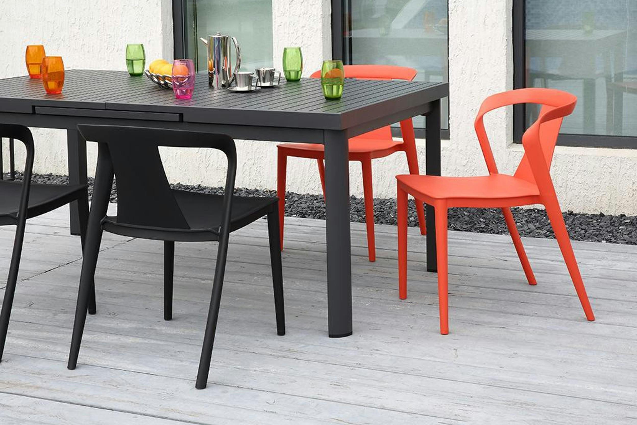 Ausziehbarer schwarzer Gartentisch mit schwarzen und roten Kunststoffstühlen