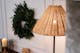 Stehleuchte mit einem Lampenschirm aus Rattan vor einem Weihnachtskranz im Homeoffice.