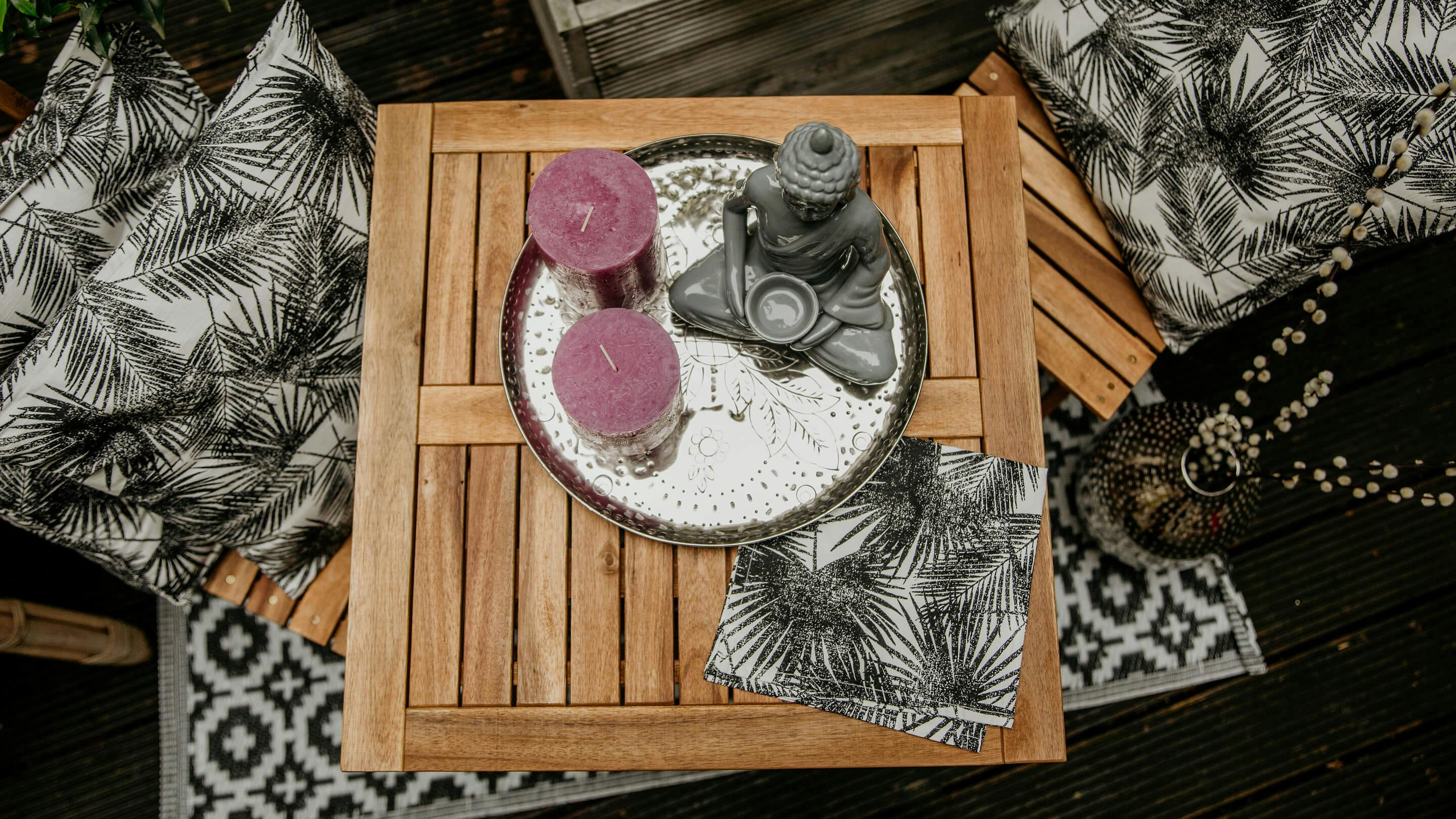 Tischecke auf Terrasse von oben gesehen: runder Deko-Teller in Silber mit Kerzen und Kerzenhalter in Grau (Marke: Butlers).