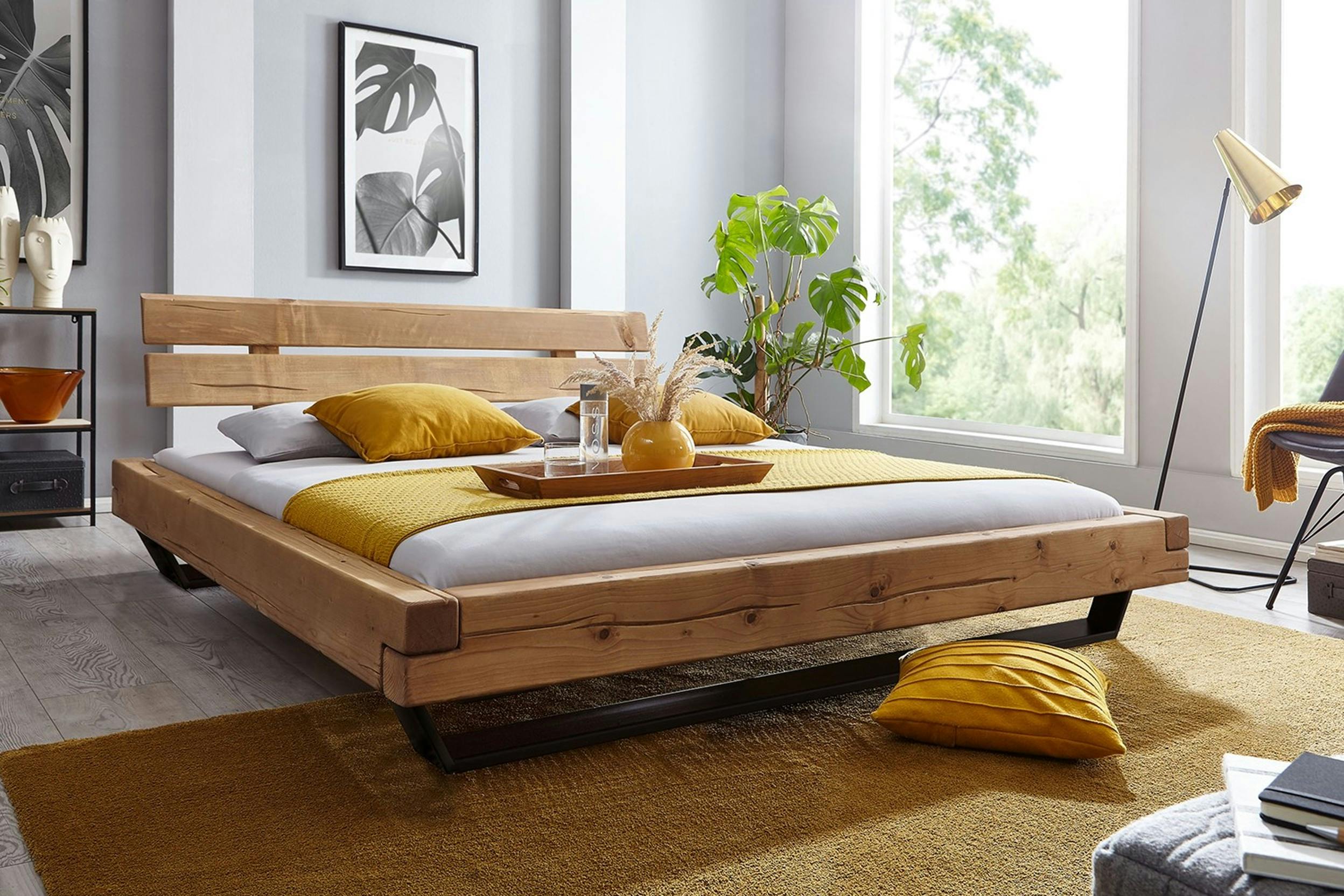 Modernes Holzbett mit gelber Bettwäsche und Frühstückstablett
