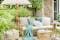 Inmitten eines gemütlichen Gartenplatzes steht ein Outdoor-Sofa aus Bambus, viele Outdoor-Textilien in Beige und Türkis sowie ein Retro-Sonnenschirm mit Fransen in Gold und Beige im orientalischen Look.