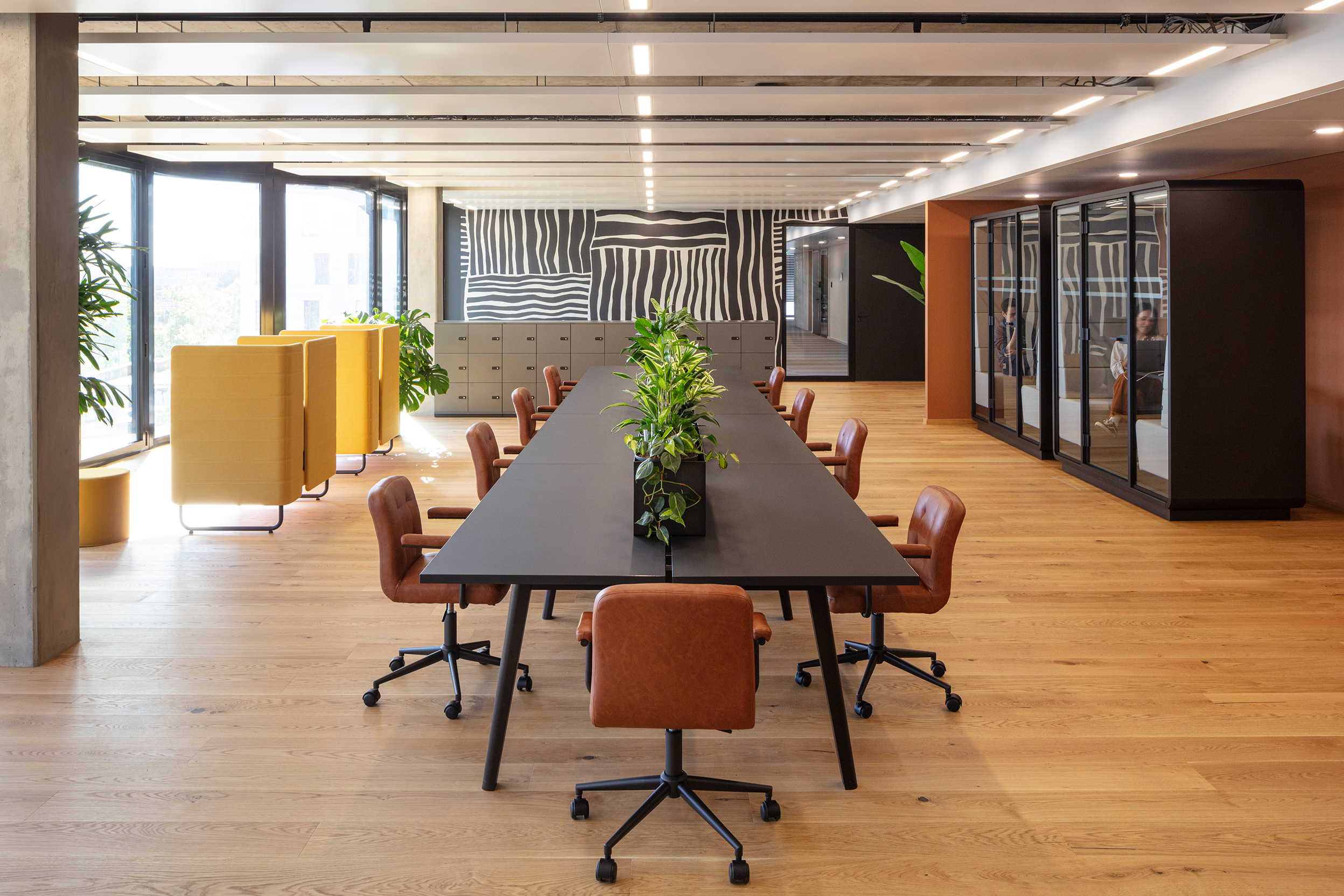 Heller, moderner Co-Working-Space mit großem Bürotisch und bequemen Drehstühlen, vielen Grünpflanzen sowie privaten Telefonboxen im home24 Office in Berlin Prenzlauer Berg.