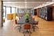 Photographie d'un espace de coworking lumineux et moderne avec un grand bureau entouré de chaises pivotantes, de plantes vertes et de cabines acoustiques situé dans le siège social d'home24 à Berlin.