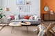Salon composé de meubles en bois et rotin et d'un canapé gris clair agrémenté de coussins colorés