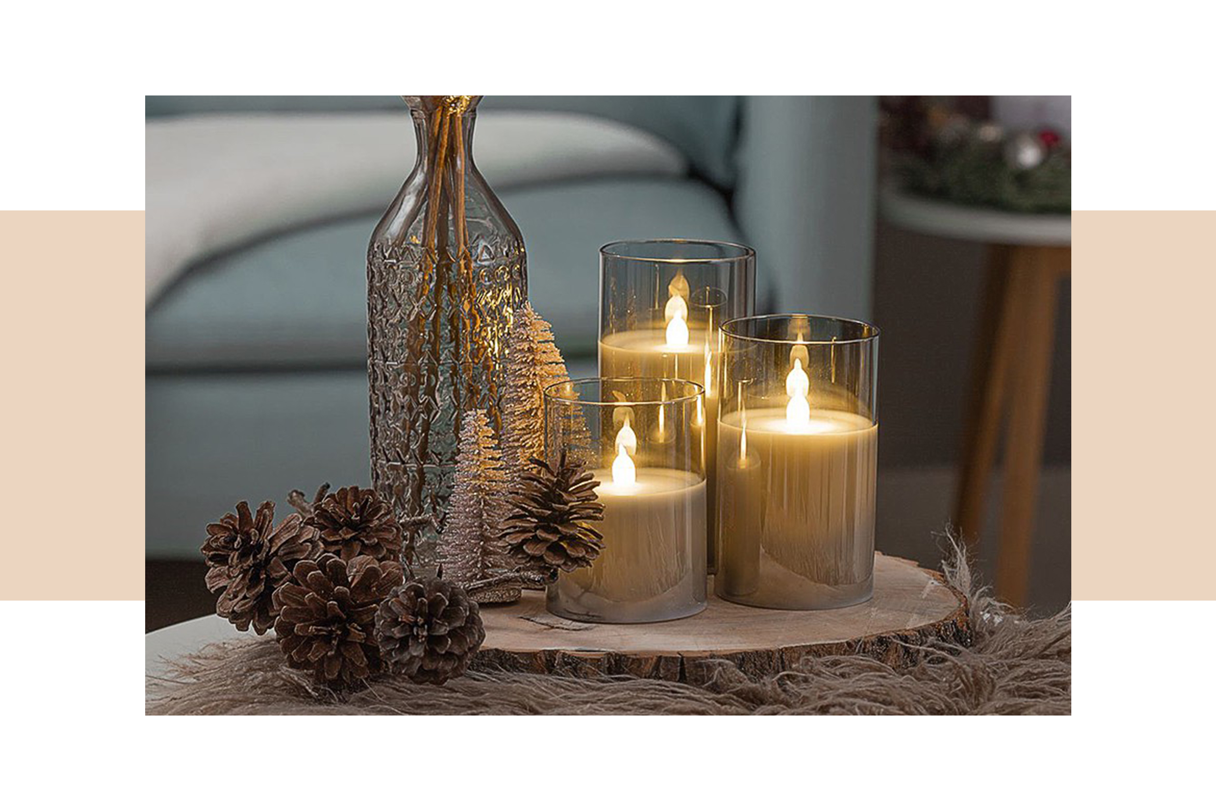 Arrangement aus drei LED-Kerzen unterschiedlicher Höhen sowie natürlicher Winterdeko auf einem Holzbrett