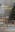 Eetkamer met meubels van Studio Copenhagen: een lichtkleurige houten eettafel met stoelen met rotan, een wit dressoir, een grijze fauteuil en glazen hanglampen; plus twee kerstbomen, kerstversiering, zwart servies, drinkglazen, zwart-witte vazen met pampagras en andere accessoires in zwart en wit.