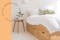 Stauraumbett aus hellem Holz mit 3 Schubkästen, weißer Bettwäsche und weißen Pendellampen über dem filigranen Nachttisch.