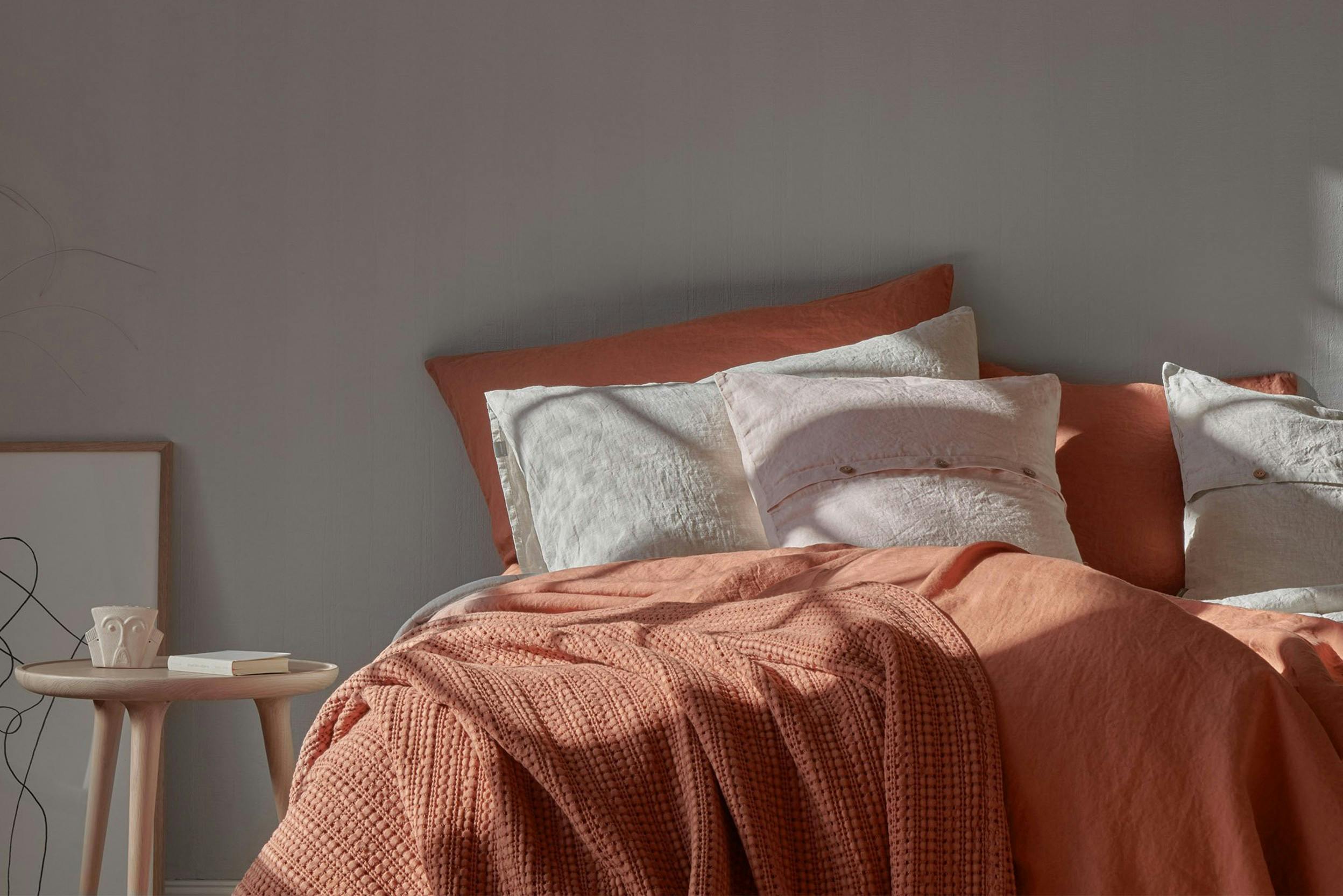 Bettwäsche aus ziegelrotem Leinen, dekoriert mit beigen und rosa Kissen